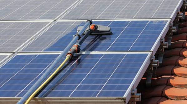 Cleaning a rooftop solar array with a soft brush and pole