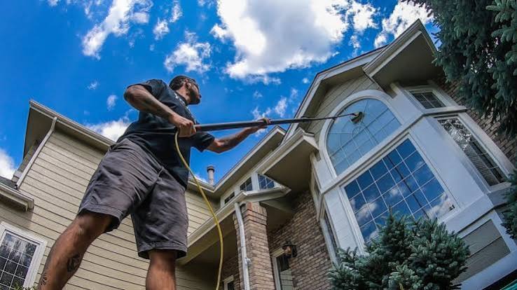 Cleaning upper-story windows on a two-story home with a water-fed pole