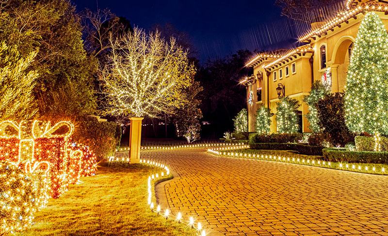Custom Christmas light installation along a driveway and lit yard displays